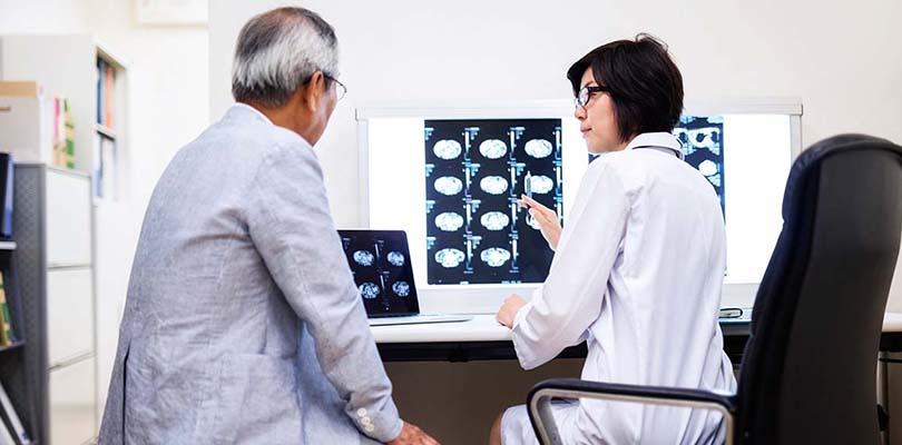 A doctor and her patient are looking at MRI brain scans