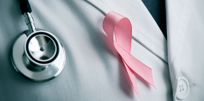 A medical professional is wearing a breast cancer ribbon