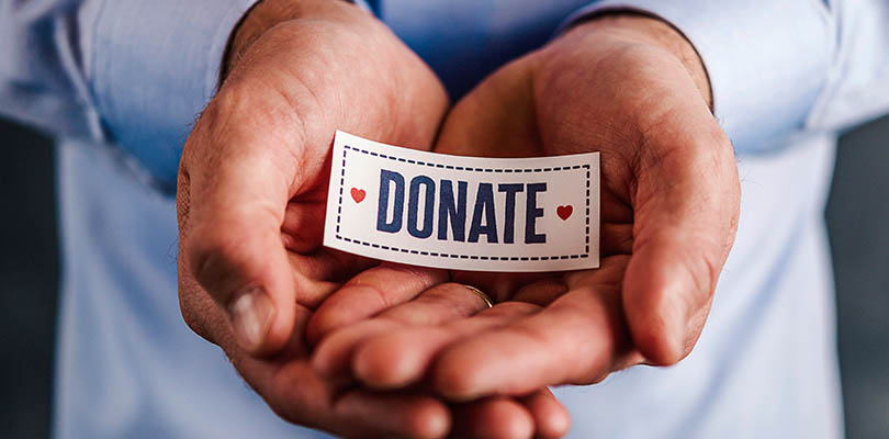 Male hands holding sign reading donate