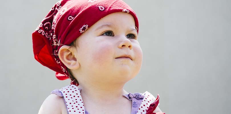 A little girl wearing a red bandanna on her head.